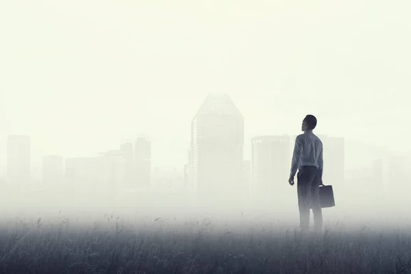 Visão traseira do jovem empresário em pé com fundo de névoa — Fotografia de Stock