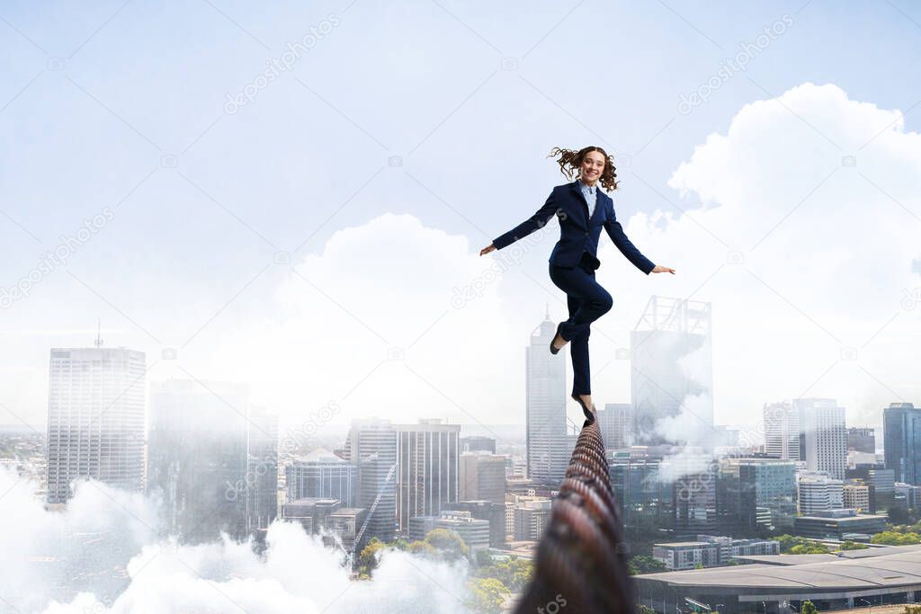 Image of businesswoman balancing on rope. Risk concept