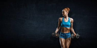 Genç ve güzel bir kız karanlık arka planda egzersiz yapıyor.