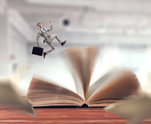 Zakenman in pak loopt bovenop een boek — Stockfoto