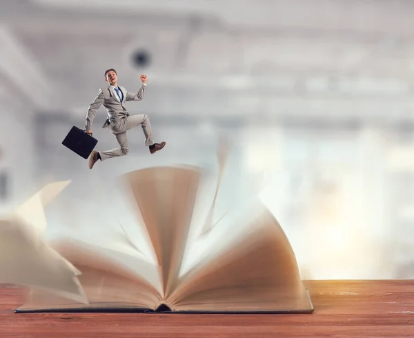 Geschäftsmann im Anzug läuft über ein Buch — Stockfoto