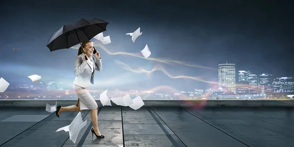 Businesswoman running with umbrella . Mixed media — Stock Photo, Image