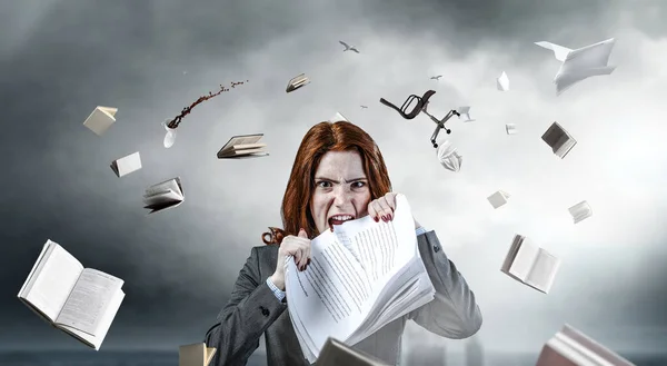 Young stressed woman ripping documents with frustrated facial expression.