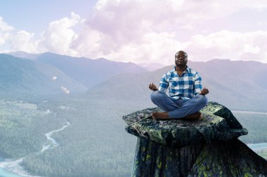 Genç siyah adam oturuyor ve meditasyon yapıyor.