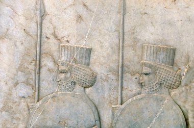 Mızrakları ve kalkanları olan Asurlu savaşçılarla dolu eski bir duvar, Persepolis, İran. UNESCO dünya mirası sahası