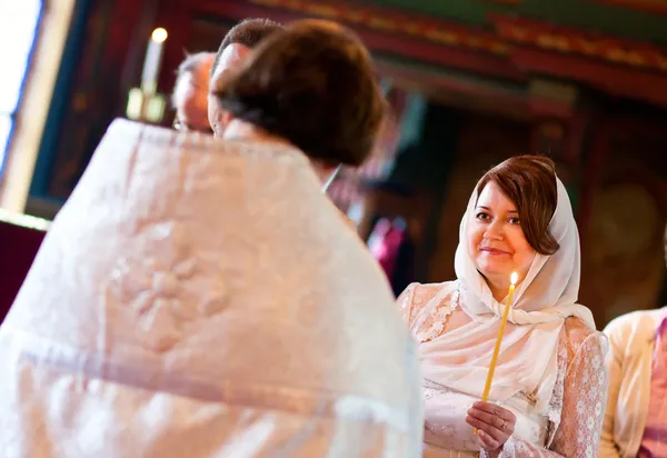 Feliz novia está escuchando al sacerdote durante la boda ortodoxa cerem —  Fotos de Stock