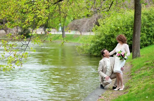 Щаслива щойно одружена пара обіймає біля води в парку — стокове фото