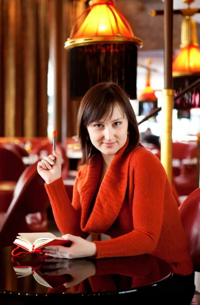 Schöne junge Frau mit ihrem persönlichen Organisator im Café — Stockfoto