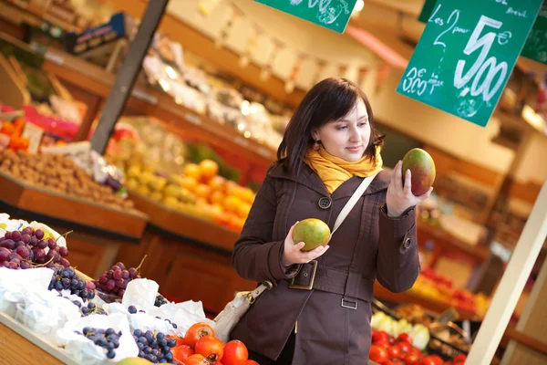 Hermosa joven mujer seleccionando mangos en el mercado — Foto de Stock