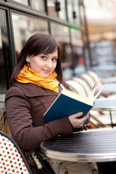 Szép, fiatal lány, olvasson egy könyvet a párizsi utca kávézó — Stock Fotó