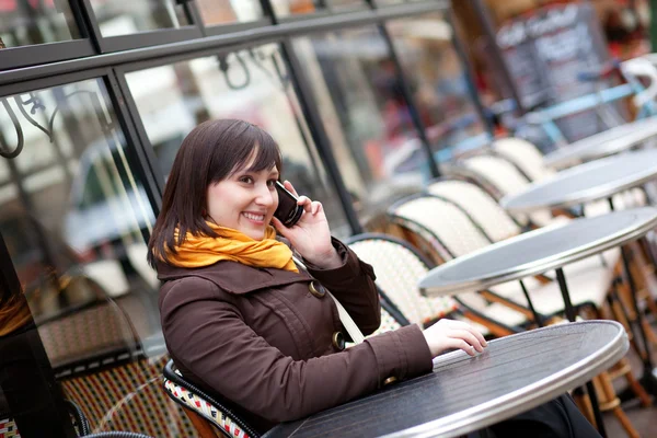 Feliz chica joven tomando el teléfono celular en la cafetería de la calle parisina —  Fotos de Stock