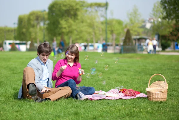 Glückliches junges Paar beim Picknick und Blasen machen — Stockfoto