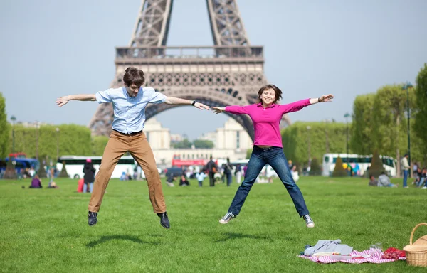 Feliz joven pareja saltando cerca de la Torre Eiffel — Foto de Stock