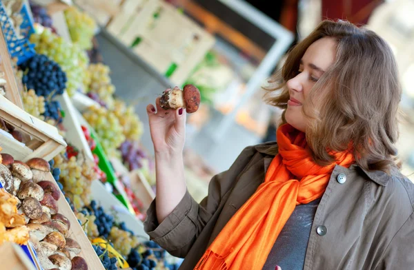 Красивая женщина покупает грибы на рынке — стоковое фото