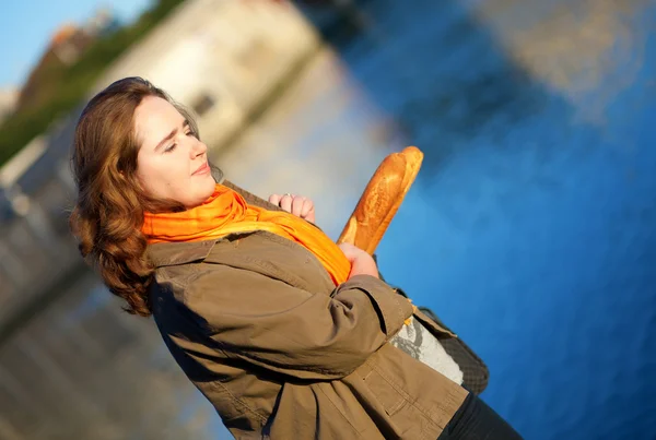 Красива дівчина з багети, ходьба на набережній Парижа — стокове фото