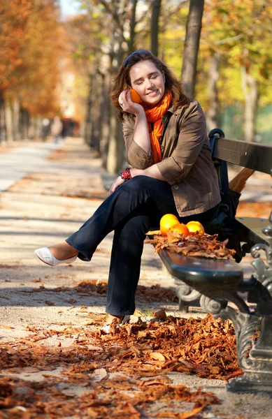 Mooie jonge vrouw met sinaasappelen in park op val — Stockfoto