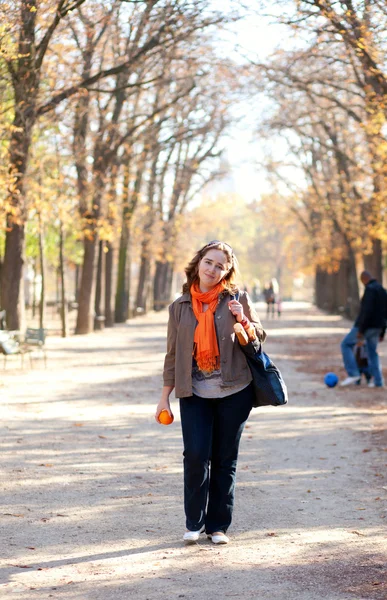 Όμορφη νεαρή γυναίκα με το πορτοκαλί στο πάρκο το φθινόπωρο — Φωτογραφία Αρχείου