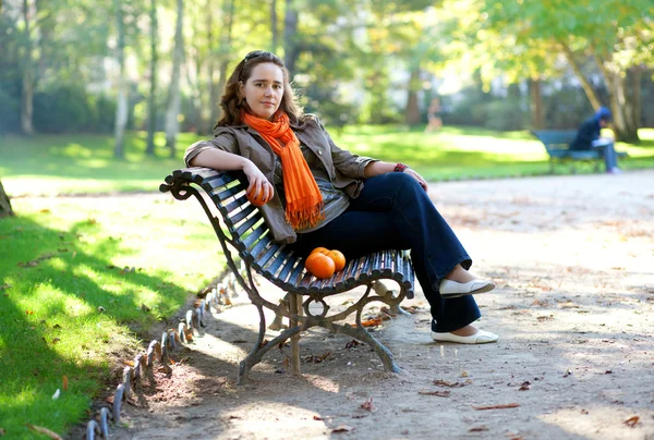 Hermosa mujer joven con naranjas en el parque en primavera u otoño — Foto de Stock