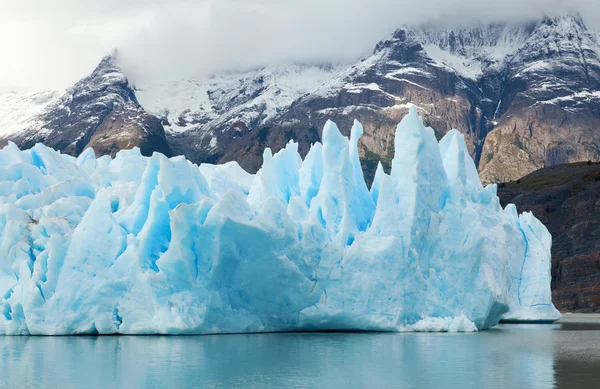 Blauwe ijsbergen en besneeuwde bergen op grijs glacier in torres del — Stockfoto