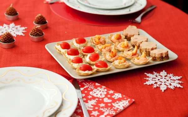 Decorated Christmas table with plate of tasty tartlets (cheese, — Stock Photo, Image