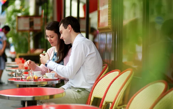 Casal feliz comendo macaroons em um café ao ar livre parisiense — Fotografia de Stock