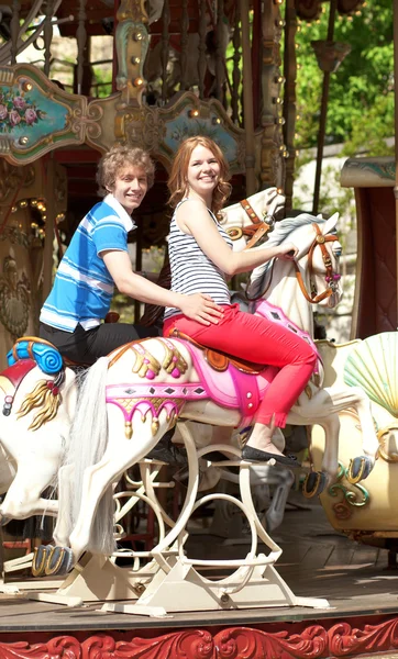 Felice giovane coppia enjyong il giro su allegro-go-round — Foto Stock