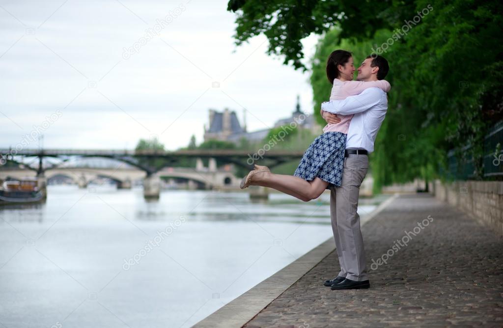 Happy romantic couple is hugging near the water, girl is jumping