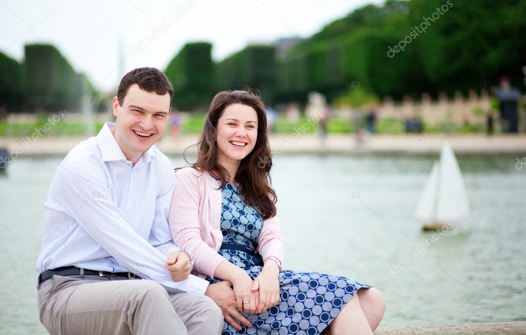 Laughing couple sitting by the water in Luxembourg garden of Par