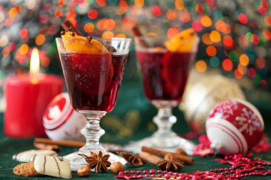 Two glasses of mulled wine with Christmas lights in the backgrou clipart