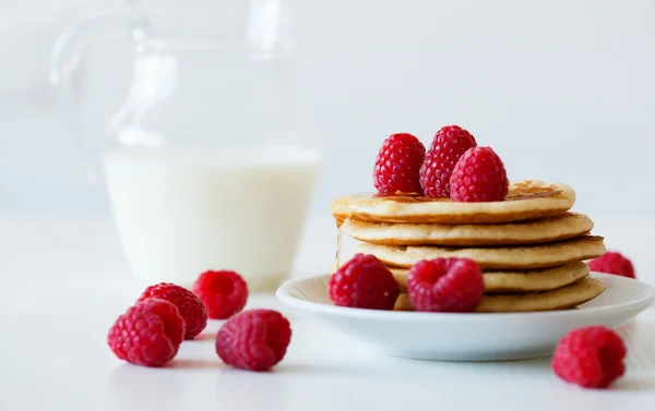 Stapel van pannenkoeken met frambozen en kruik van melk — Stockfoto