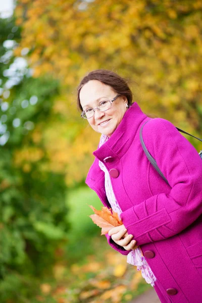 Beautiful middle aged woman in park by fall — Stock Photo, Image