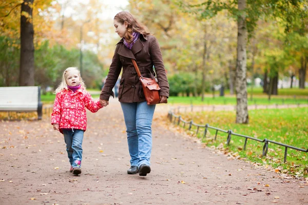 Mother and daughter walking in autumn park together — Stock Photo, Image