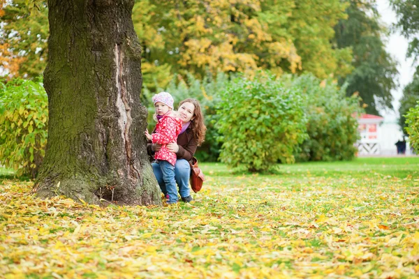 Hermosa madre e hija cerca del árbol en el parque de otoño —  Fotos de Stock