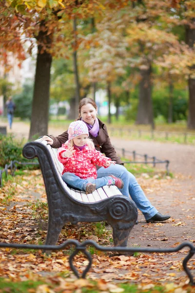 Mother and her adorable daughter sitting on a bench — Stock Photo, Image