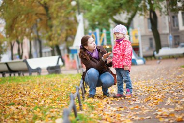 Anne ve kızı yaprakları ile parkta oynarken