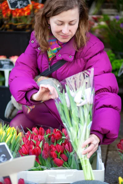 Bella giovane donna che seleziona i fiori al mercato — Foto Stock