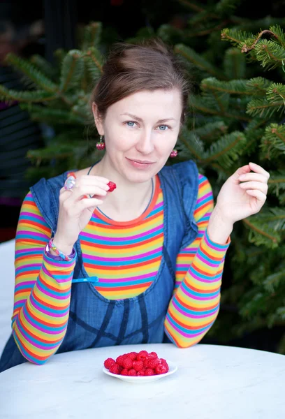 Beautiful girl in bright clothes eating raspberry — Stock Photo, Image