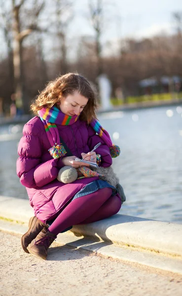 Belle fille en vêtements lumineux écrire quelque chose dans son notebo — Photo