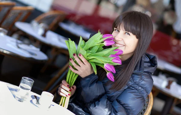 Smiling brunette lady with beautiful tulips in Parisian street c — Stockfoto