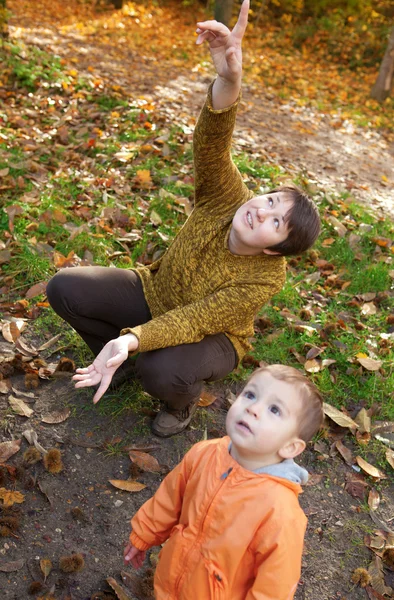 Mother and son in autumn forest, looking at plane in the sky — Stock Photo, Image