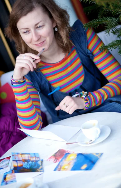 Beautiful girl writing Christmas cards in a cafe — Stock Photo, Image