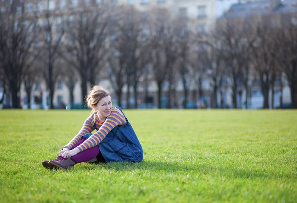 Красива молода дівчина в яскравому одязі сидить на траві — стокове фото