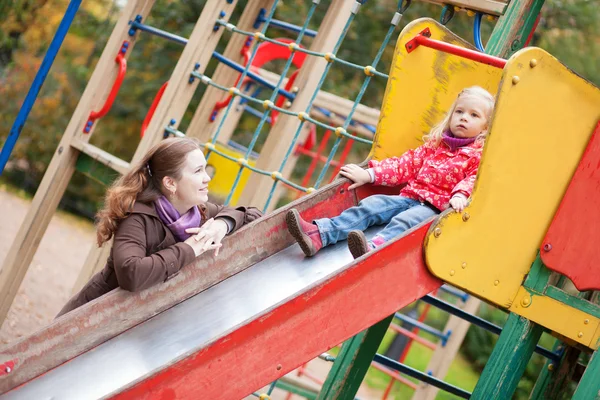 Mother looking at her daughter on slide — Stock Photo, Image