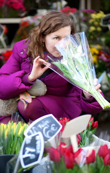 Beautiful young woman selecting flowers at market — Stock Photo, Image