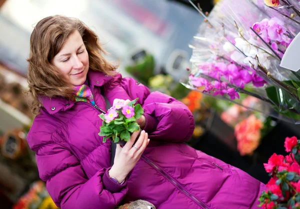 Beautiful girl in bright clothes choosing flowers at market — Stock Photo, Image