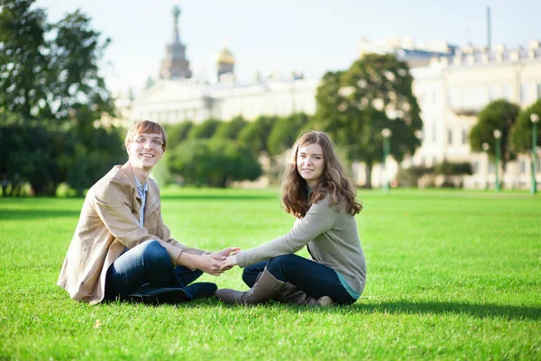 Lyckliga paret sitter på gräset tillsammans — Stockfoto