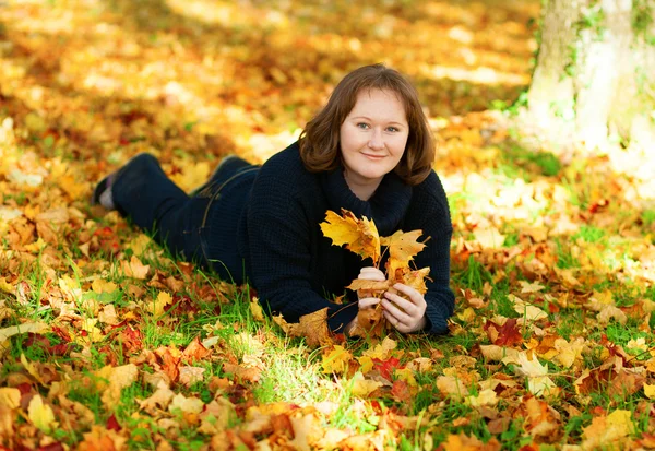 Menina feliz deitada no chão no parque em um dia de outono — Fotografia de Stock