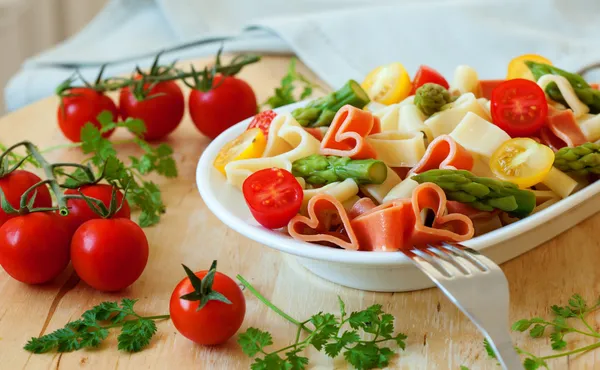 Jantar romântico. Delicioso macarrão em forma de coração com tomates, asp — Fotografia de Stock