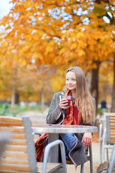 Souriant jeune femme boire du vin chaud dans un café en plein air dans un — Photo