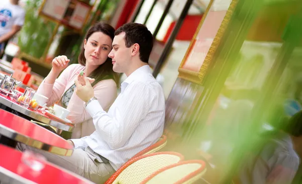 Casal feliz comendo deliciosos macaroons em um parisiense ao ar livre ca — Fotografia de Stock